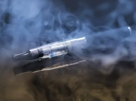 Cigarette électronique et vape entourées de fumée, accompagnement au sevrage par hypnose