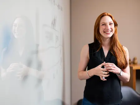 Professionnelle souriante travaillant sereinement devant un tableau, illustration de la prévention du burn-out en sophrologie à Boulogne-Billancourt.